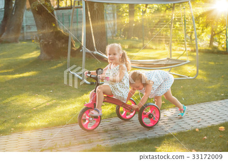 Cute little blond girls riding a bicycle in summer 33172009