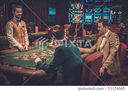 Upper class friends gambling in a casino. 33174065