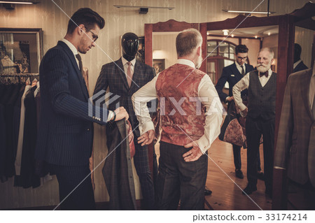 Tailor and client measuring custom made garment 33174214