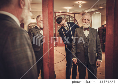 Tailor and client measuring custom made garment 33174221