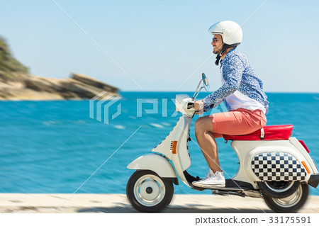 Handsome man posing on a scooter in a vacation 33175591