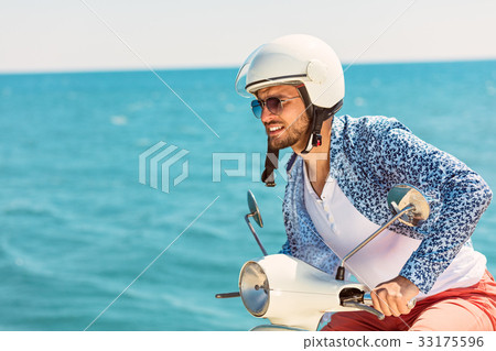 Handsome man posing on a scooter in a vacation 33175596