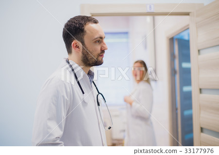 pensive young doctor in white coat holding 33177976