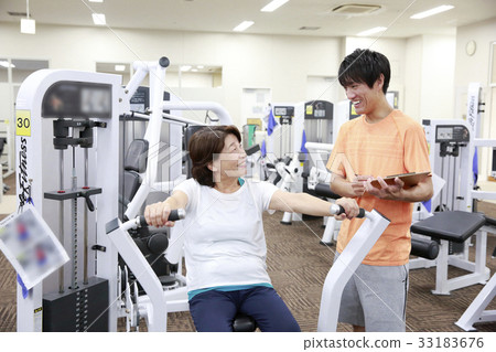 Elderly woman getting advice on machine training in a sports club 33183676