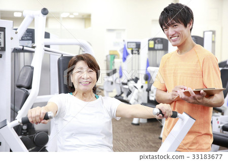 Elderly woman getting advice on machine training in a sports club 33183677