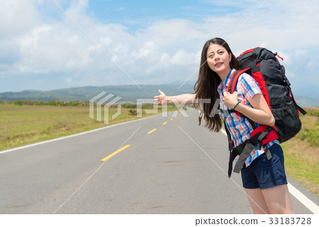 woman carrying travel backpack standing on road woman carrying travel backpack standing on road 33183728