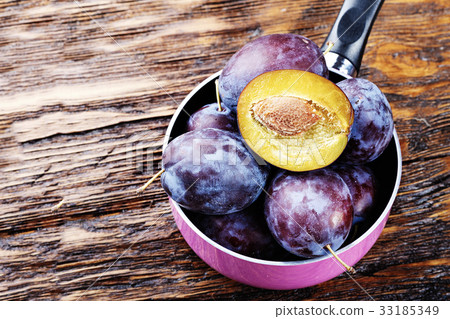 Ripe plums on a brown wooden table 33185349