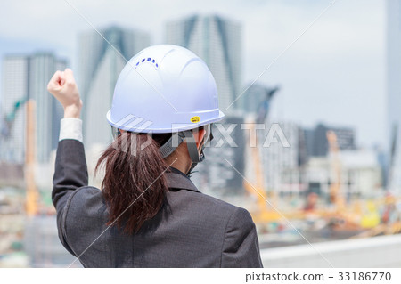 Woman in a suit wearing a helmet wearing a guts pose towards the construction site 33186770