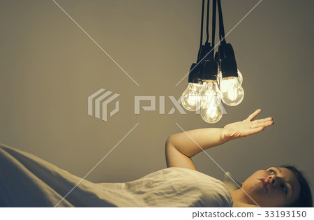A girl lies in bed under big light bulbs. Insomnia 33193150