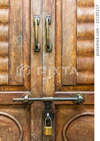 Old latch and padlock on a wooden door Old latch and padlock on a wooden door 33195217