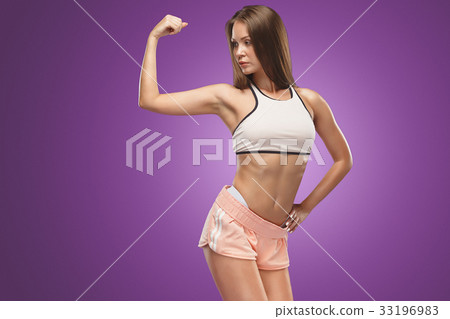 Muscular young woman athlete posing at studio 33196983