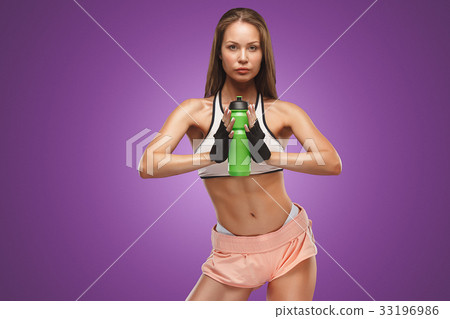 Muscular young woman athlete posing at studio 33196986