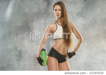 Muscular young woman athlete posing at studio 33197010