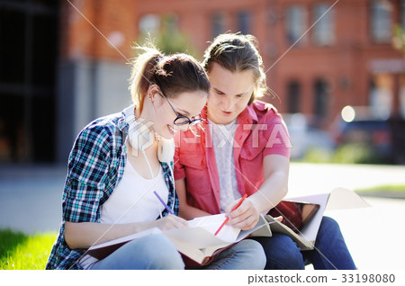 Young happy students with books and notes outdoors Young happy students with books and notes outdoors 33198080