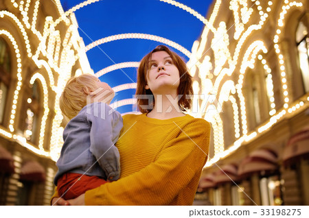 Young mother and her little son enjoy beautiful city illumination Young mother and her little son enjoy beautiful city illumination 33198275