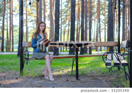 Young woman reading a book and relaxing at the Young woman reading a book and relaxing at the 33205349