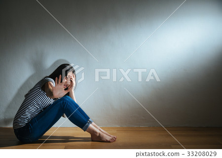 woman sitting on wood floor hand cover head 33208029