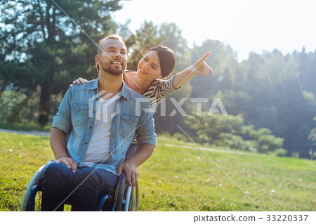 Wife drawing her disabled husbands attention to Wife drawing her disabled husbands attention to 33220337