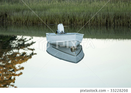 Small boat moored and reflecting in a lake  33228208