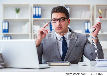 Businessman smoking in office at work Businessman smoking in office at work 33234663