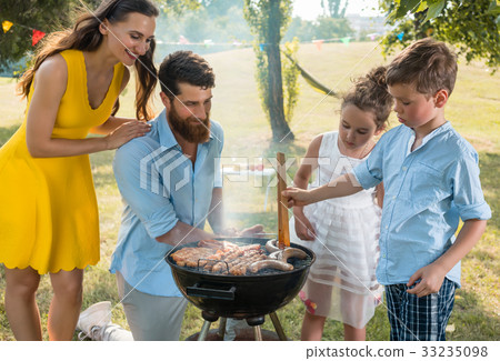 Father and son preparing meat on charcoal barbecue Father and son preparing meat on charcoal barbecue 33235098