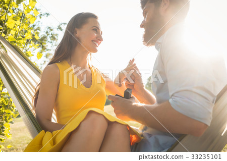 Happy man putting engagement ring on the finger of Happy man putting engagement ring on the finger of 33235101