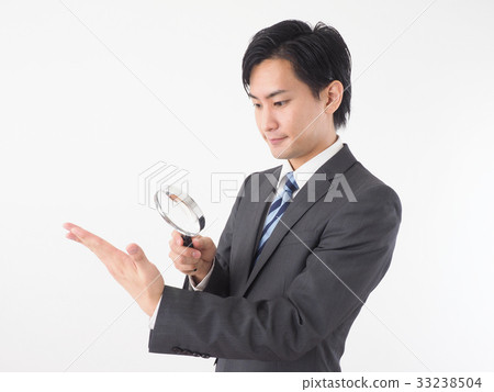 Businessman looking at hand with loupe 33238504