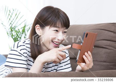 A young lady who operates a smartphone lying on the sofa 33239806
