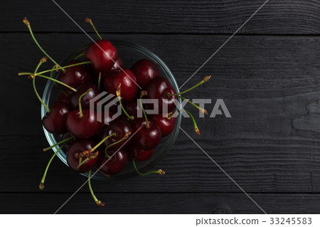 Cherry in a glass plate top view on a black 33245583