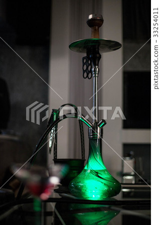 The green hookah is standing on the table. 33254011