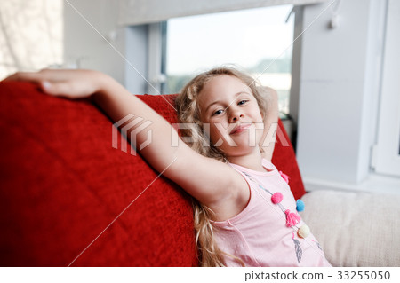 Happy 6 year old girl is sitting on red chair in 33255050