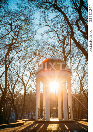 Sun at sunset shining through gazebo in city park 33281244