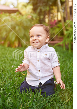 Little boy sitting on grass Little boy sitting on grass 33283117