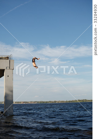 Man jumping into sea from pier 33284930