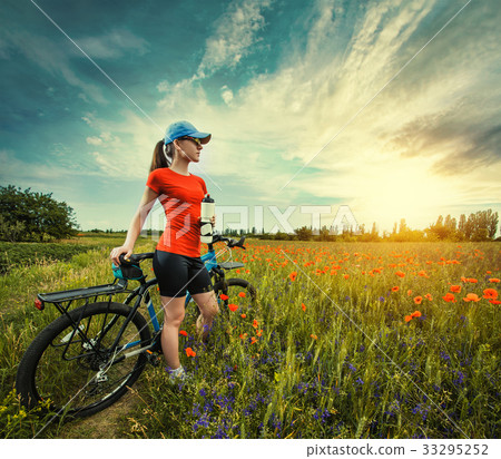 woman riding a bicycle on a blooming poppy meadow woman riding a bicycle on a blooming poppy meadow 33295252