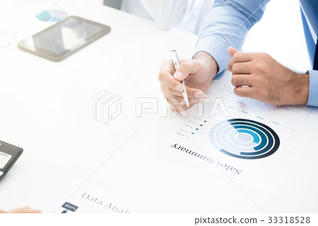 Businessman holding pen while reading graph 33318528