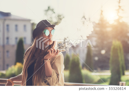 Pretty young hipster woman in black hat vape ecig Pretty young hipster woman in black hat vape ecig 33320814