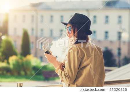Pretty young hipster woman in black hat vape ecig 33320816