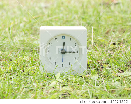 Square simple white clock on the grass 12:15 33321202