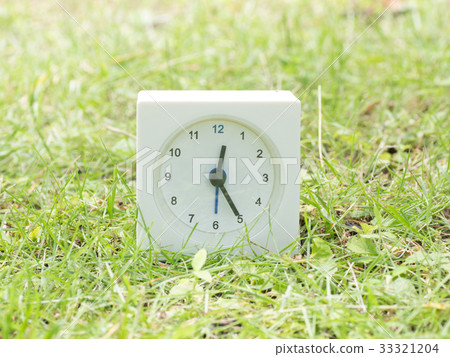 Square simple white clock on the grass 12:25 33321204