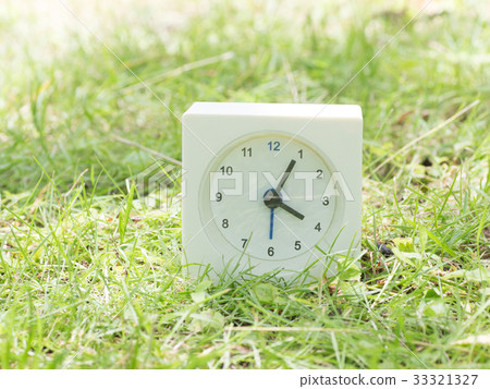 Square simple white clock on the grass 4:05 33321327