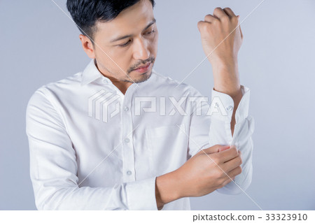 A man is fastening the buttons of his white shirt A man is fastening the buttons of his white shirt 33323910