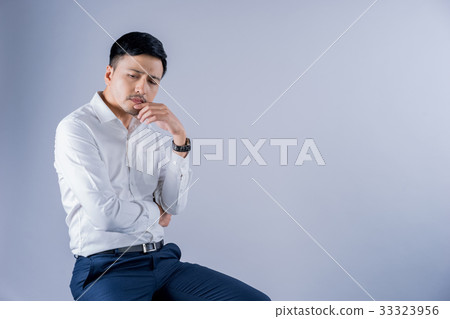 a businessman is sitting and thinking on gray background 33323956