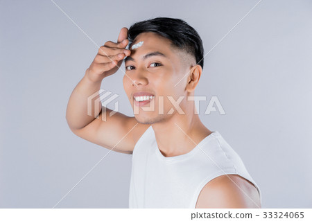 Young man is applying cream on his forehead Young man is applying cream on his forehead 33324065