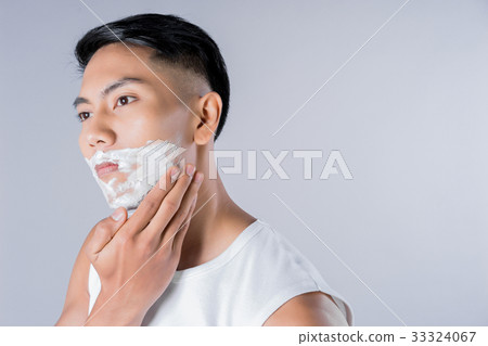 Young businessman is applying shaving cream on his face 33324067