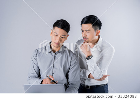 two young men are looking at laptop and thinking 33324088