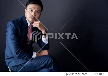 a handsome man is looking at camera and thinking on black background 33324095