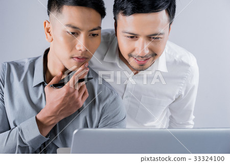 two young men are looking at laptop and thinking 33324100