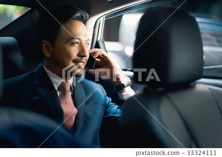 Asian handsome businessman on call in car, smiling Asian handsome businessman on call in car, smiling 33324111