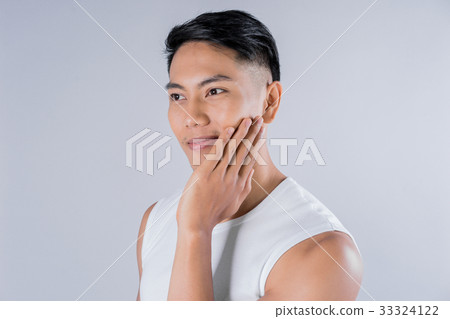 a young man is touching his face and smiling a young man is touching his face and smiling 33324122